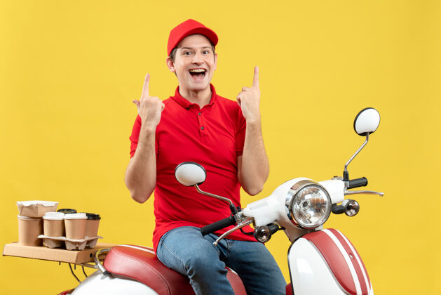 男子正面是一个穿着红色上衣 戴着帽子 面带微笑的年轻人 在黄色背景上向上传达命令摩托车运动指点