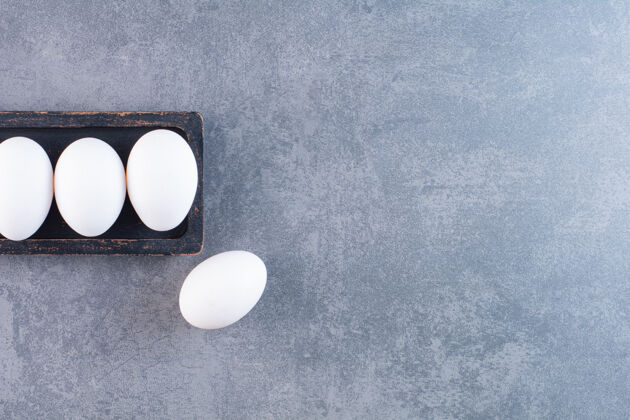 顶视图黑盘子的有机白鸡蛋放在石桌上背景生的食物