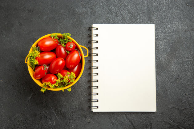 食物顶视图桶樱桃番茄和莳萝花和一个笔记本在黑暗的背景蔬菜配料笔记本