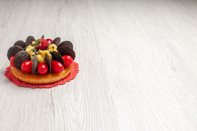 食物左上角白色木桌上的红色椭圆形蕾丝doily上有浆果巧克力蛋糕花木头新鲜
