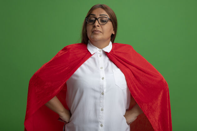 超级英雄自信的中年女超人戴着眼镜低头把手放在臀部隔离在绿色眼镜穿着自信