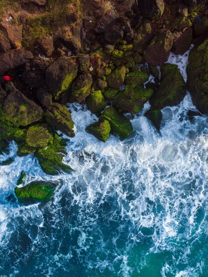 海洋垂直俯视空中拍摄的波浪蓝色的海洋对岩石悬崖沙滩高
