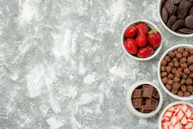 浆果在灰白色地面的右侧 有糖果 草莓 苦味的牛奶巧克力 谷类食品和可可的顶视图碗水果饮食遥远