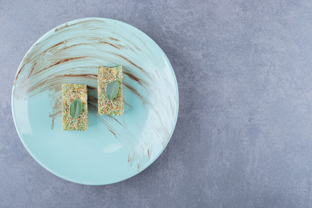 斋月土耳其美食rahatlokum的顶视图 灰色背景上蓝色盘子上有榛子糖喜悦自然