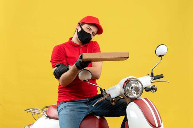 面罩俯视图：精疲力尽的快递员身穿红色上衣 戴着帽子手套 戴着医用面罩 坐在摩托车上 手里拿着订单帽子自行车人