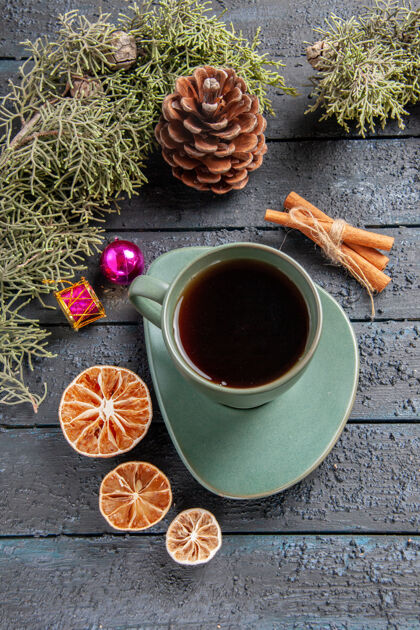 杯子顶视图一杯茶冷杉树枝圣诞玩具干橘子肉桂黑木桌上深色的肉桂