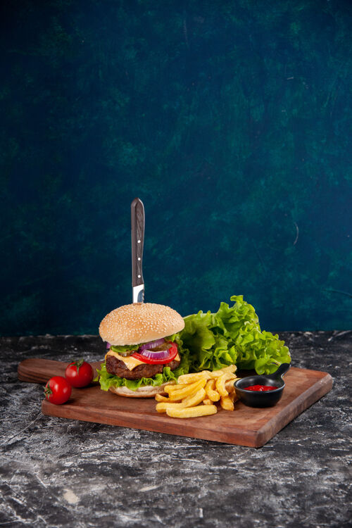 食物刀在肉三明治和炸番茄干胡椒在木板番茄酱深蓝色的表面刀沙拉薯条