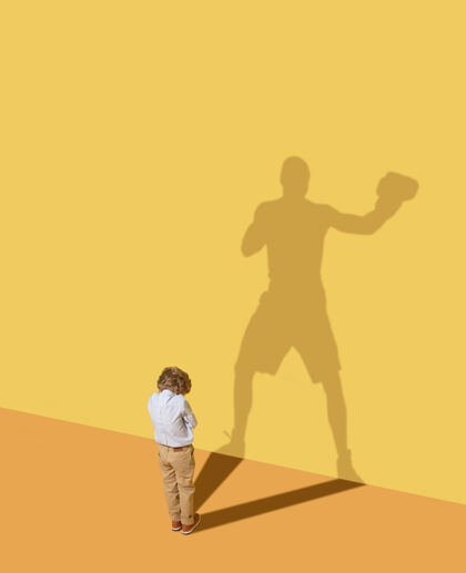 高国王的成功未来的冠军童年和梦想的概念概念形象与儿童和阴影在黄色的工作室墙上小男孩想成为一名拳击手 建立一个体育事业男孩拳击手人