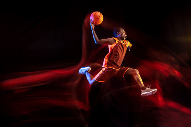 球员在胜利前一跳非洲裔美国青年篮球运动员的红队在行动和霓虹灯在黑暗的工作室背景概念的运动 运动 能源 动态 健康的生活方式比赛力量运动员