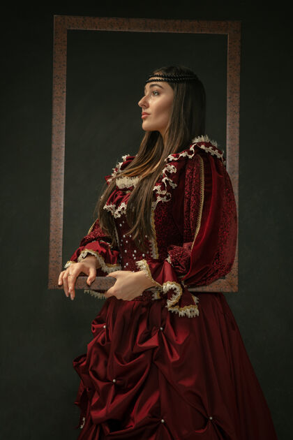 砖骄傲身着红色复古服装的中世纪年轻女子站在深色背景上的肖像女模特 公爵夫人 皇室成员比较时代 现代 时尚 美丽的概念公平服装服装