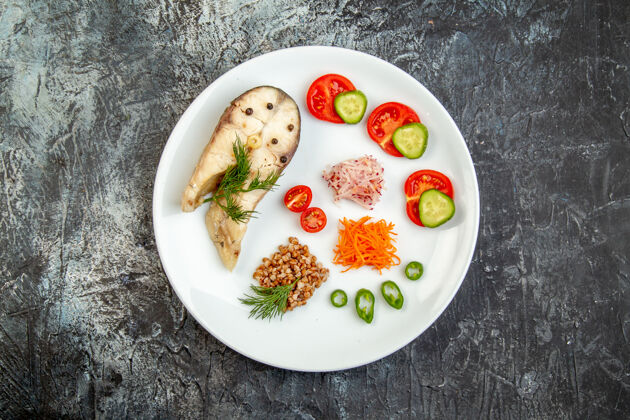 盘子冰面上白色盘子上煮鱼荞麦和绿色蔬菜的俯视图水煮鱼容器晚餐