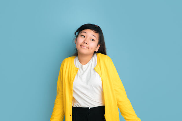 人在蓝色工作室背景上孤立的亚洲青少年肖像美丽的深褐色女性模特 随意的长发人类情感的概念 面部表情 销售 广告不确定女孩主管英俊