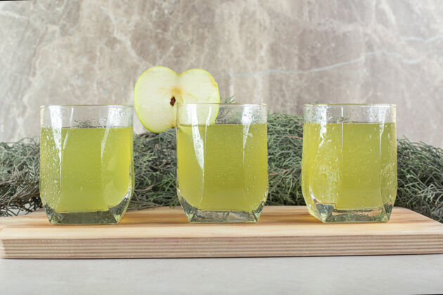 美味三杯果汁加苹果片放在木板上食品松枝新鲜