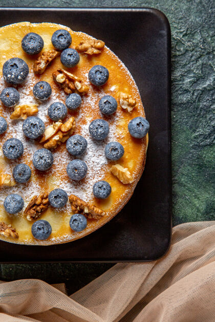水果顶视图美味的蜂蜜蛋糕与蓝莓和核桃内板黑暗的表面核桃餐蓝莓