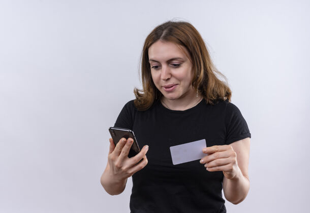 年轻高兴的年轻休闲女子拿着手机和信用卡在隔离的空白处与复印空间持有女士手机