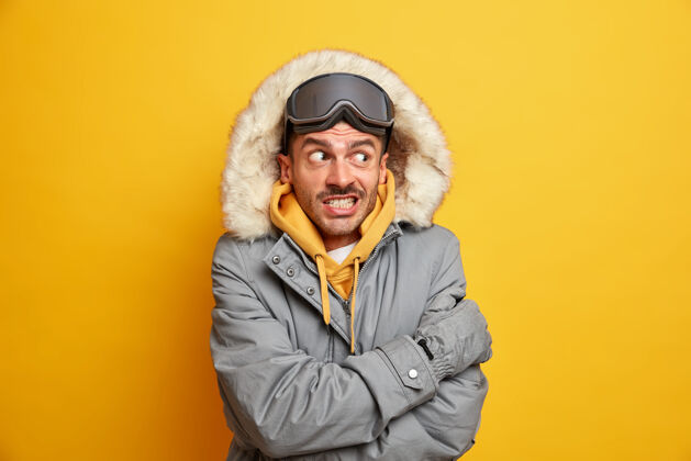 温暖帅哥觉得外面很冷 寒天里浑身发抖 抱着自己暖咬牙 穿着带兜帽的冬衣夹克季节滑雪