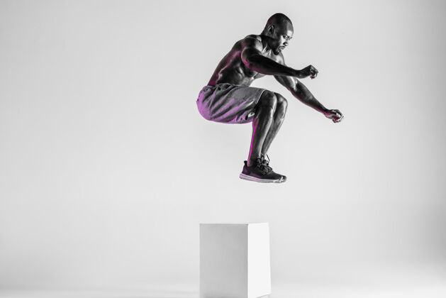 握为情感而战在灰色工作室背景下接受年轻的非裔美国人健美训练穿着运动服的肌肉男模特跳跃运动 健美 健活方式的概念运动力量健身