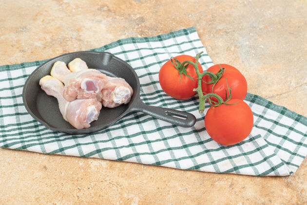 西红柿一个深色的平底锅 里面有生鸡腿和西红柿美味食物蔬菜