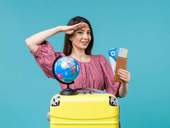 微笑前视图女性在旅行中拿着钱包和机票上蓝色背景的女性旅行度假海上旅行女人航行前面
