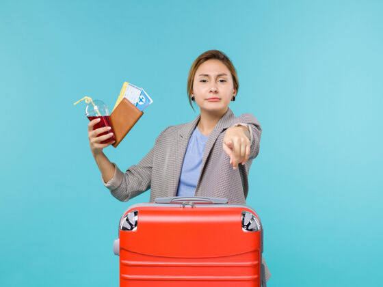 航行正面图：度假中的女性拿着果汁和蓝色背景的机票旅行度假海上飞机女人假期果汁