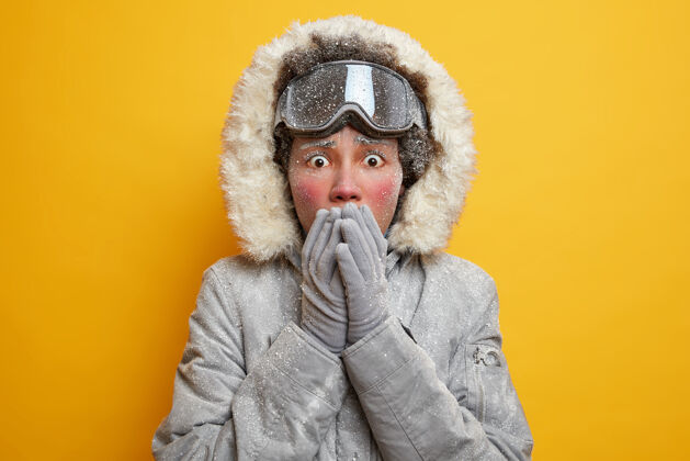 霜冻在斯堪的纳维亚半岛的季节性户外活动中 一个紧张的年轻女子用手捂住嘴 穿着连帽夹克 戴着覆盖着白霜的手套 感觉很冷凉爽北极娱乐