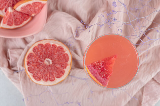 果汁一杯果汁和新鲜的葡萄柚在粉红色的布上水果美味鸡尾酒