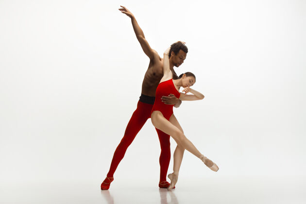 舞蹈优雅的经典芭蕾舞者在白色的工作室背景上独立地跳舞一对穿着鲜红衣服的舞者就像是酒和牛奶的结合优雅 艺术家 动作 动作的概念运动优雅舞蹈