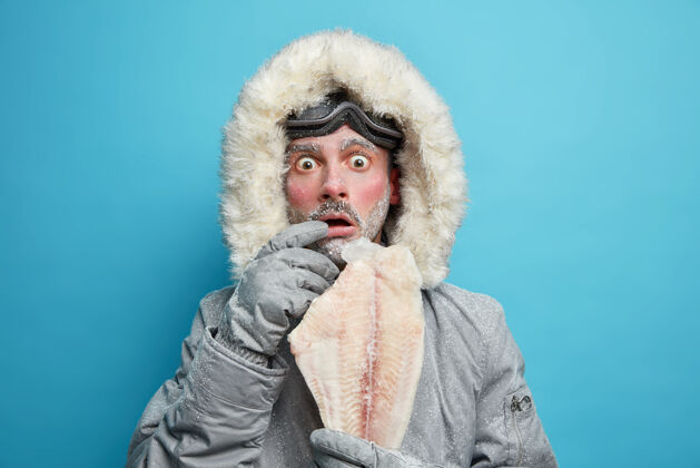 冬天情绪震惊 穿着冬季外套的冷冰冰的男人抱着冻鱼 在北方的低温下感觉很冷家伙外套极端