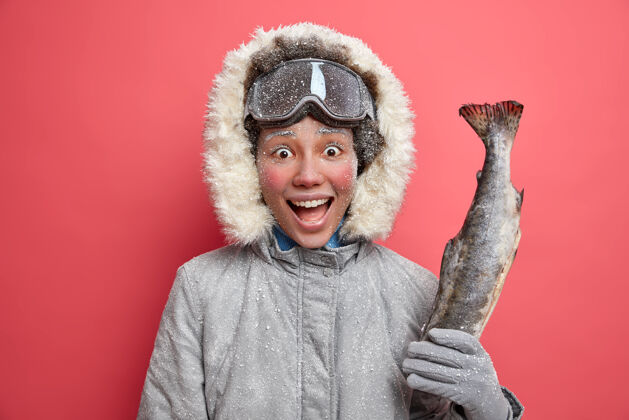高兴积极的女人在冬天钓鱼穿着暖和的夹克戴滑雪板护目镜在低温下有积极的休息人欢呼手套