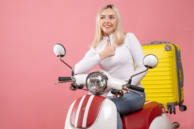 前面前视图快乐的金发女孩骑着轻便摩托车竖起大拇指坐漂亮快乐