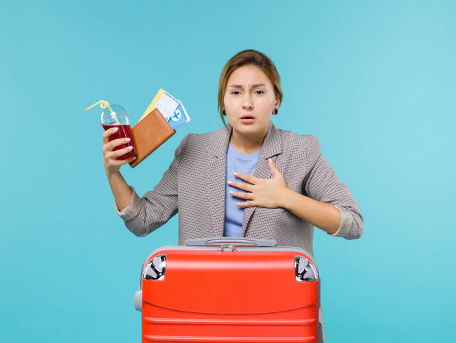 果汁前景度假中的女性拿着果汁和机票在蓝色背景上咳嗽旅行度假海上飞机看法旅行航行