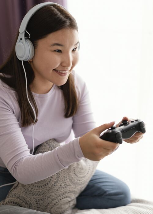 游戏笑脸女孩在床上玩电子游戏视频游戏乐趣玩