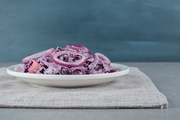 食物切碎的紫洋葱和卷心菜沙拉放在一个白色的陶瓷盘子里晚餐午餐餐具