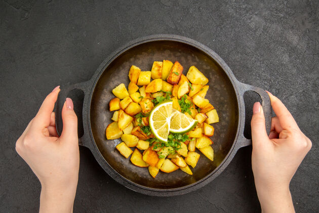 切片顶视图美味的炸土豆内锅柠檬片在黑暗的表面里面健康一餐