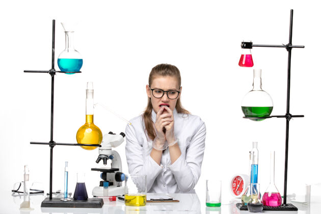 浅白前视图穿着医疗服的女化学家坐在浅白的背景上 解决了化学大流行性冠状病毒套装化学前面