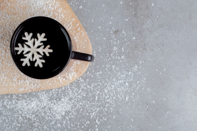 热饮两个甜甜圈和一杯带有雪花装饰的茶 放在大理石桌上撒着椰子粉的木板上美味雪花冬天