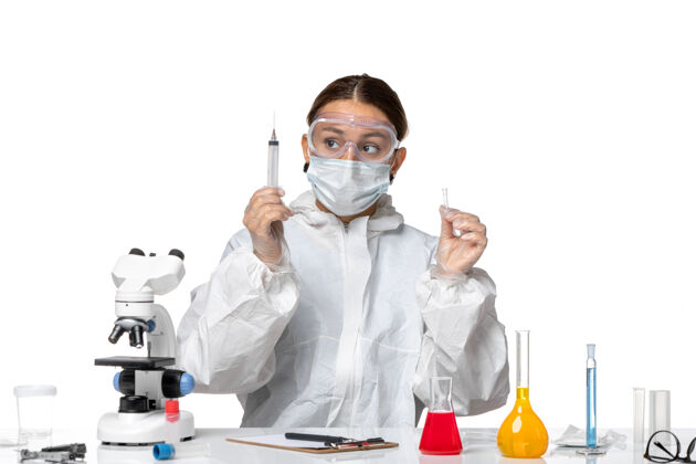 工作前视图穿着防护服 戴着口罩的女医生正在注射浅白色背景的病毒药物covid大流行实验室外套防护视图