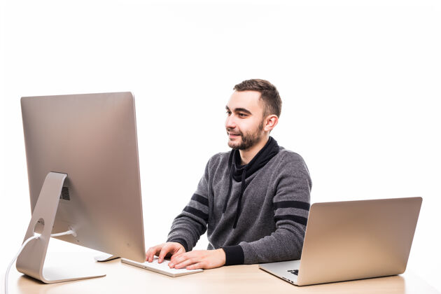欢呼自信的年轻企业家坐在桌子旁 笔记本电脑和个人电脑都是白色的笔记本电脑商务笔记本电脑