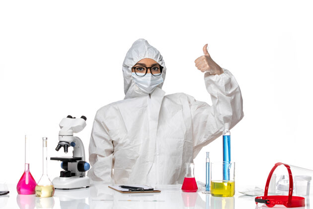 人前视图穿着特殊防护服的女化学家坐在浅白背景上 解决了化学冠状病毒大流行白药坐
