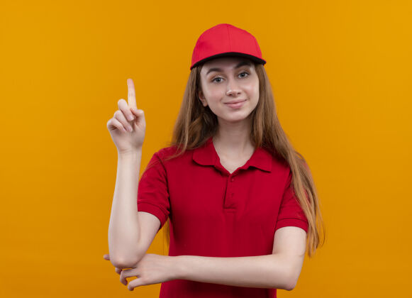 提高穿着红色制服的自信的年轻女送货员举起手指站在孤立的橙色空间年轻手指红色