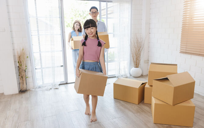 包装幸福亚洲人一家抱着纸板箱跑进新家搬迁概念亚洲女性房间