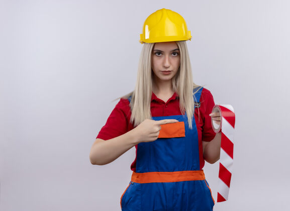 制服自信的年轻金发工程师建筑工女孩穿着制服拿着透明胶带指着它在孤立的空白空间与复制空间磁带苏格兰年轻