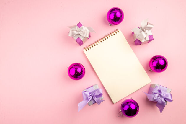 礼物顶视图的小礼物圣诞树玩具和记事本上粉红色的表面花玩具记事本
