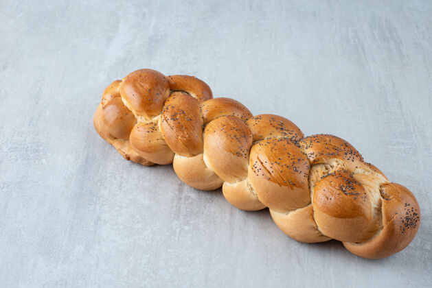 美味白色编织的面包放在石头桌上面包编织麦片