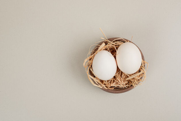 碗新鲜的鸡蛋和干草放在木碗里家禽鸡蛋干草