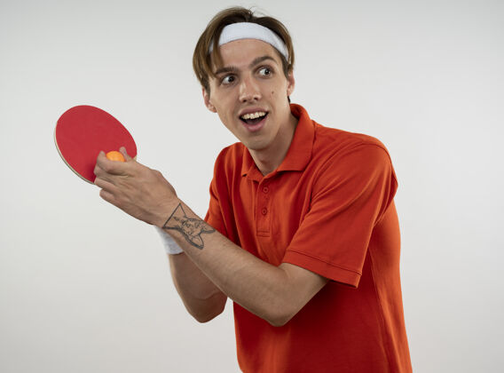 球带着微笑的年轻人戴着头带和手腕拿着乒乓球拍和球头带人乒乓球