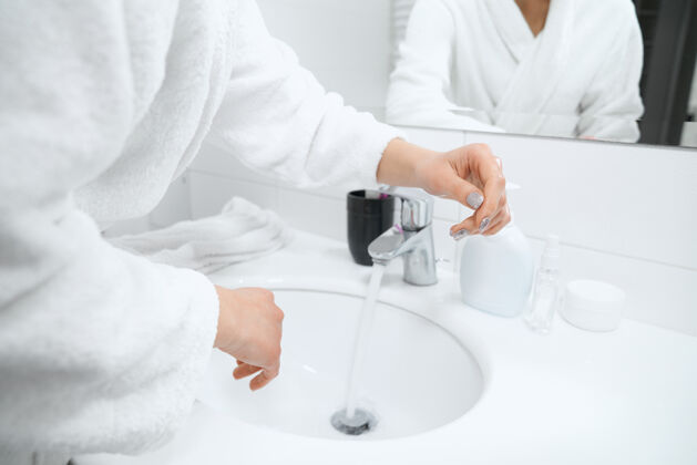细菌穿着白色长袍的女人站在水槽边洗手卫生手健康