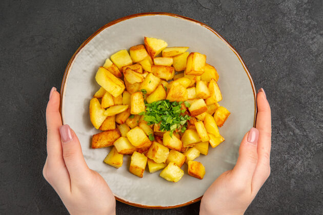 可食用的水果美味的炸土豆在黑暗的表面与绿色盘子里俯瞰薯条油里面