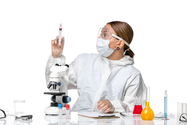 大流行正面图：女医生穿着防护服 戴着口罩 手持白色背景上的注射健康冠状病毒大流行医生实验室外套注射