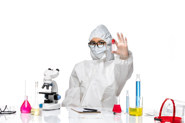 套装正面图身着特殊防护服的女化学家在白桌子上拿着烧瓶病毒健康化学病毒桌子医疗白色